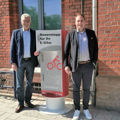  v.l. Wobau-Geschäftsführer Detlef Koch und Prokurist Andrè Baars übergeben die neue Ladestation, die von Einheimischen und Touristen gleichermaßen genutzt werden kann.